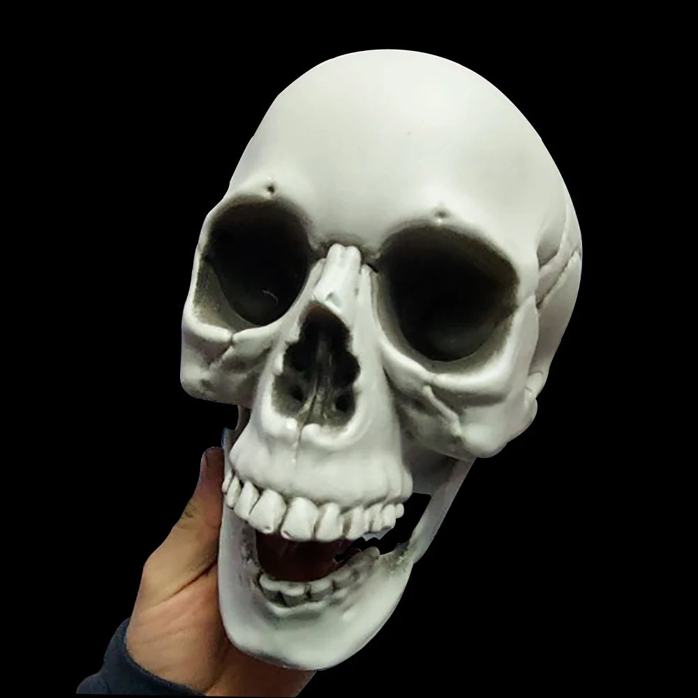 White skull mask held by a hand against a black background