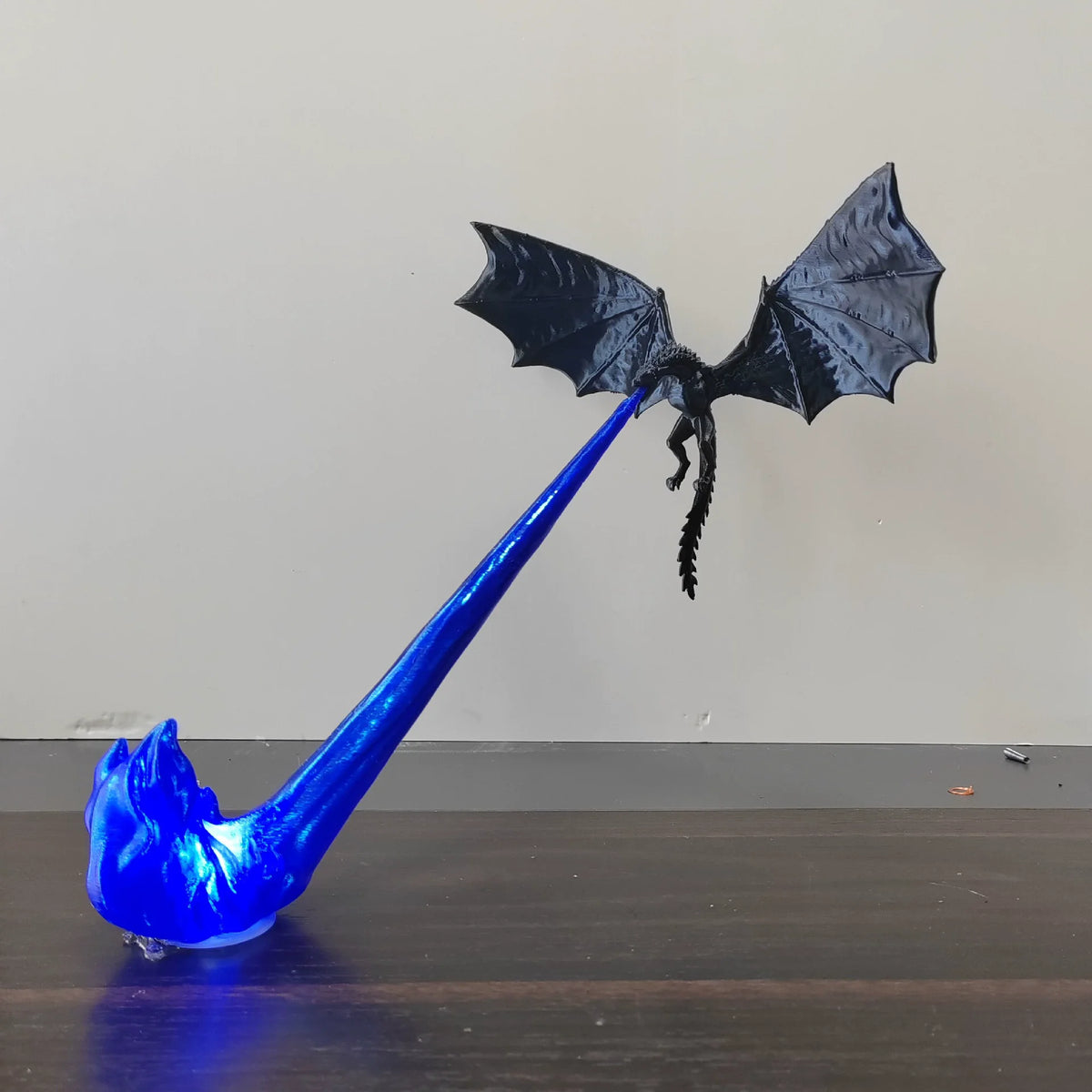 Blue dragon-shaped object on a wooden surface with a plain background