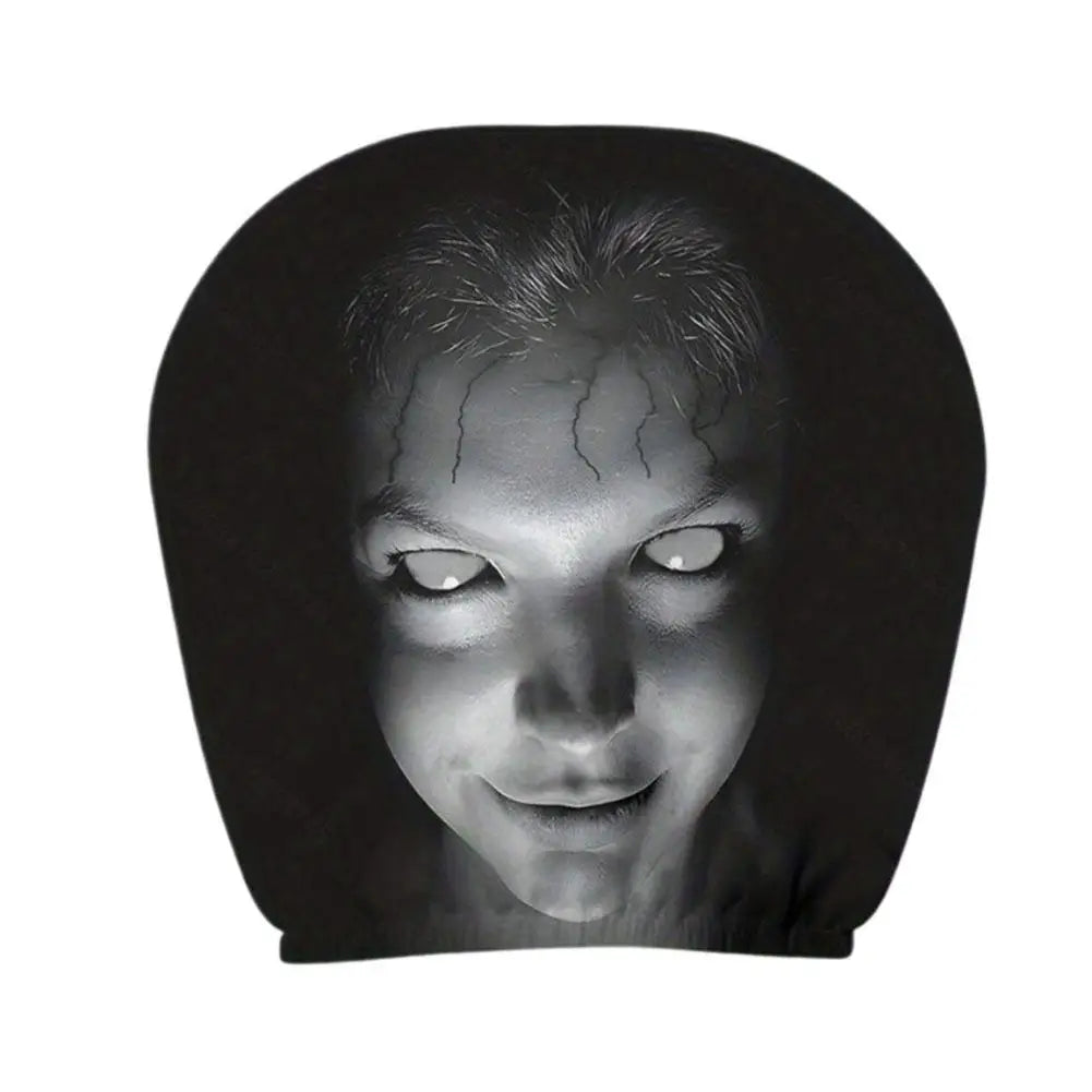 A black novelty headrest or pillow featuring a high-contrast black and white graphic print of a creepy face with glowing white eyes and cracks on the forehead, shown against a plain white background.