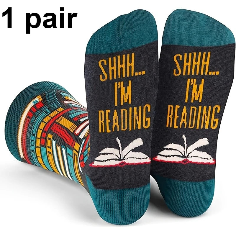A pair of novelty crew socks shown on a white background with a '1 pair' text overlay. The socks feature a dark charcoal gray body with yellow text reading 'SHHH.
