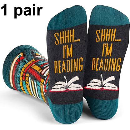 A pair of novelty crew socks shown on a white background with a '1 pair' text overlay. The socks feature a dark charcoal gray body with yellow text reading 'SHHH.