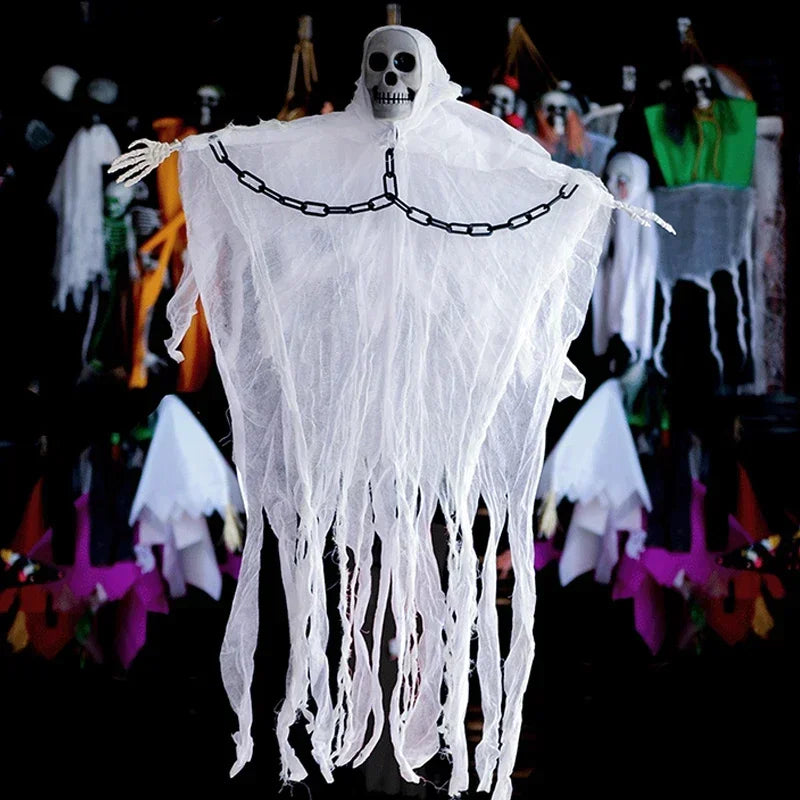A Halloween decoration of a skeleton draped in a tattered white sheet, with skeletal hands and a black chain across the chest, set against a dark background with other spooky decorations.
