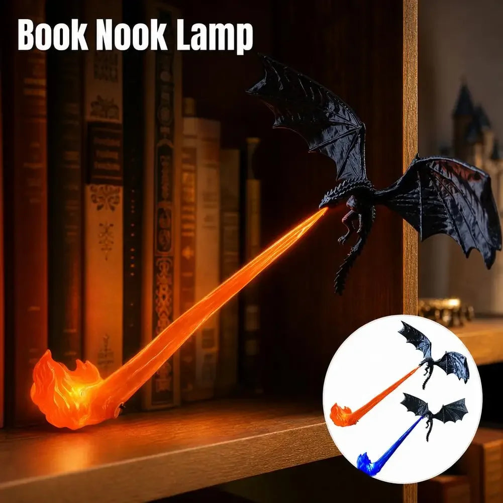 A dragon-shaped book nook lamp with a black winged dragon body and a glowing orange flame-like nook, shown on a wooden bookshelf beside books. Text at the top reads 'Book Nook Lamp,' and a circular inset shows alternate color options with blue and orange flames.